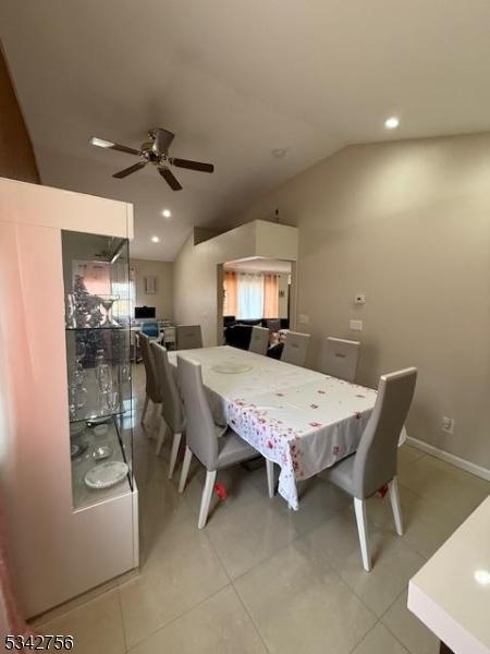 dining space with baseboards, vaulted ceiling, recessed lighting, light tile patterned flooring, and a ceiling fan