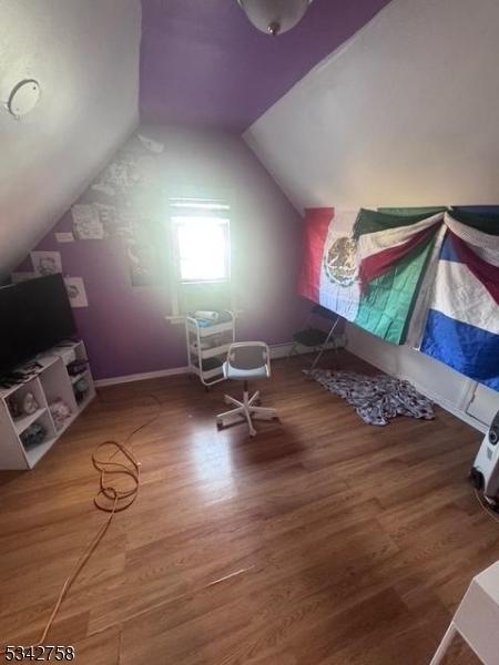 interior space featuring lofted ceiling, baseboards, and wood finished floors