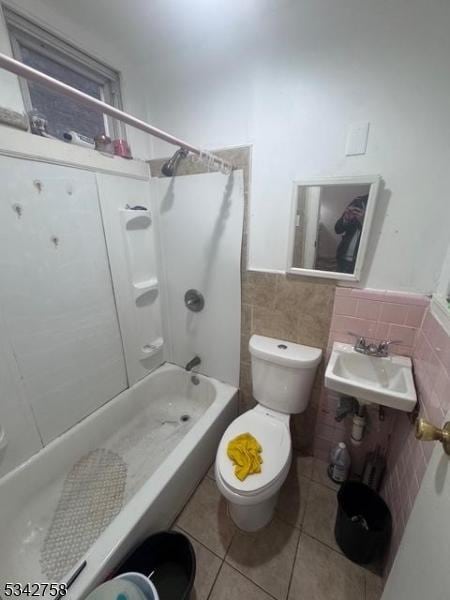 bathroom featuring tile patterned flooring, a sink, toilet, and tile walls