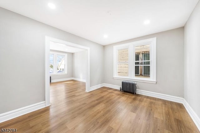 empty room with recessed lighting, baseboards, radiator heating unit, and wood finished floors