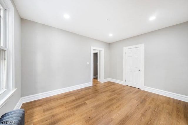 empty room featuring light wood finished floors, recessed lighting, and baseboards