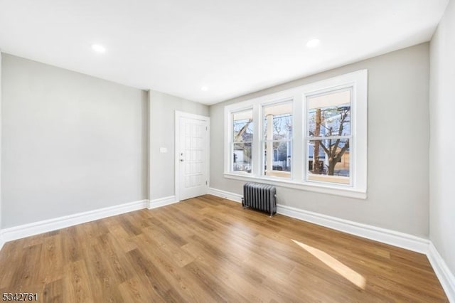 unfurnished room with radiator, baseboards, wood finished floors, and recessed lighting