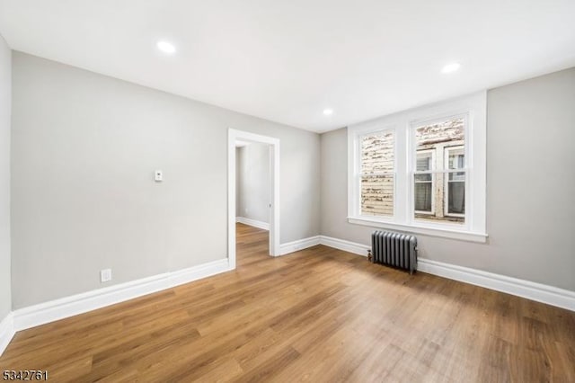 spare room featuring radiator, light wood finished floors, baseboards, and recessed lighting