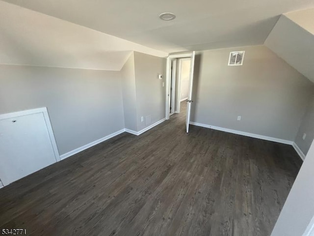 additional living space with dark wood-type flooring, visible vents, and baseboards