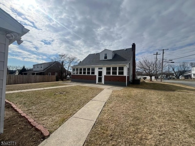 view of front of property featuring a chimney, a front yard, fence, and brick siding