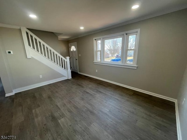 unfurnished living room featuring dark wood-style flooring, recessed lighting, ornamental molding, baseboards, and stairs