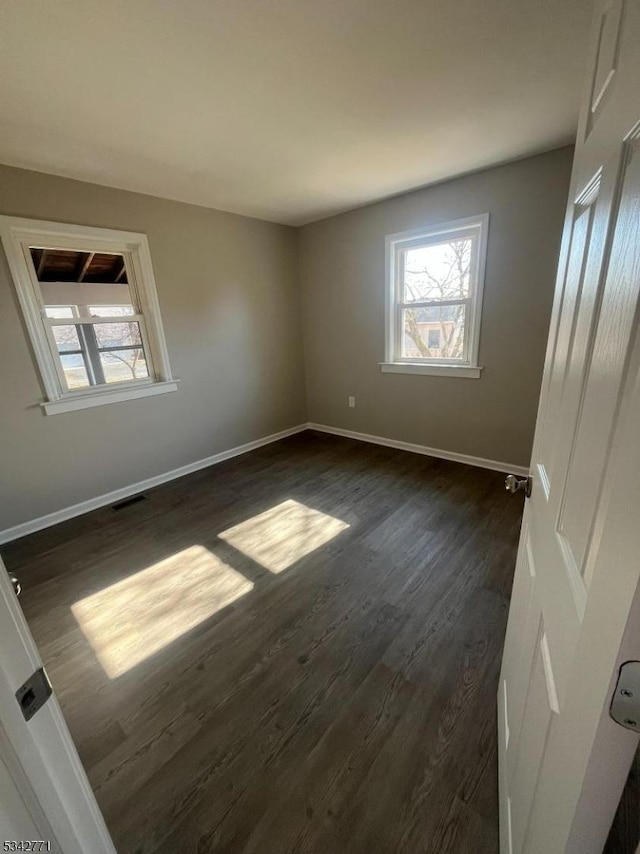 unfurnished bedroom with dark wood-style floors, baseboards, and visible vents