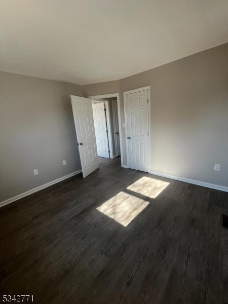 unfurnished bedroom featuring dark wood finished floors and baseboards