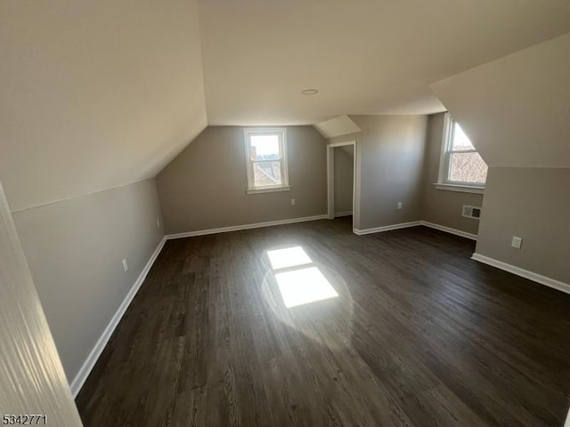 bonus room featuring lofted ceiling, dark wood-style flooring, visible vents, and baseboards