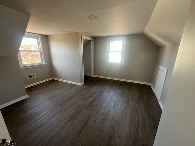 additional living space featuring dark wood-type flooring, visible vents, and baseboards