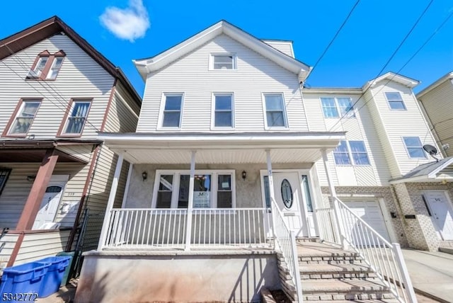 townhome / multi-family property with covered porch, driveway, and an attached garage