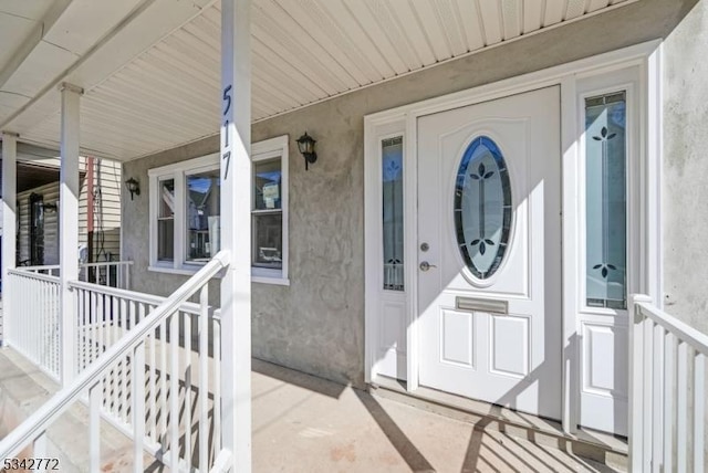 doorway to property featuring a porch and stucco siding