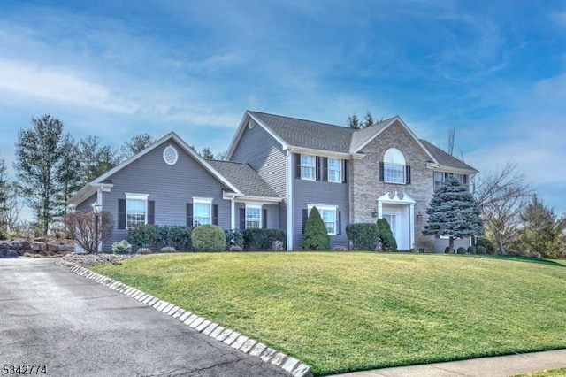 colonial inspired home with stone siding and a front yard