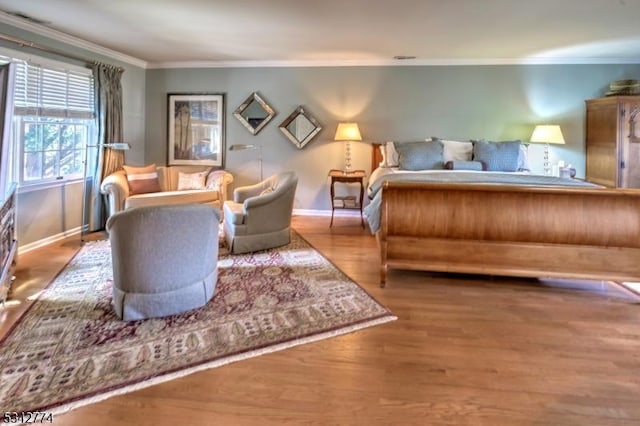 bedroom featuring baseboards, wood finished floors, and crown molding