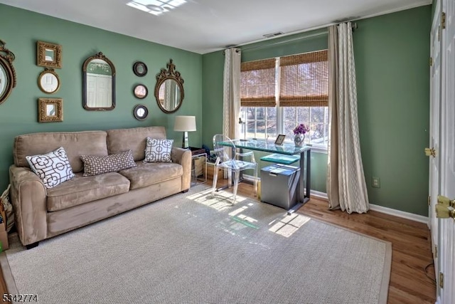 living area with wood finished floors, baseboards, and visible vents