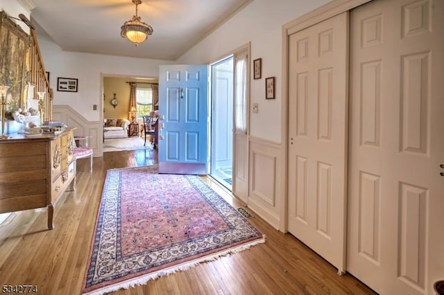 foyer with a decorative wall, wood finished floors, and a wainscoted wall