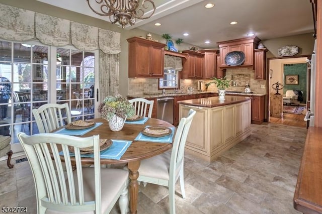 kitchen with backsplash, stainless steel dishwasher, an inviting chandelier, and a wealth of natural light