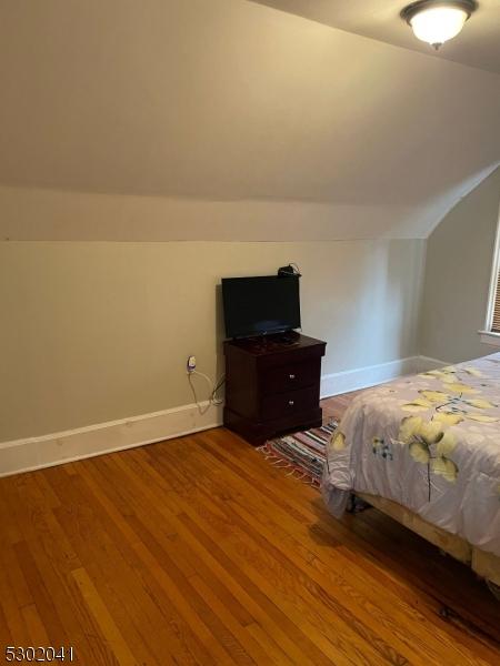 unfurnished bedroom with baseboards, vaulted ceiling, and wood finished floors