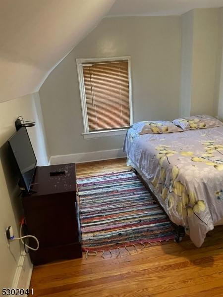 bedroom with lofted ceiling, wood finished floors, and baseboards