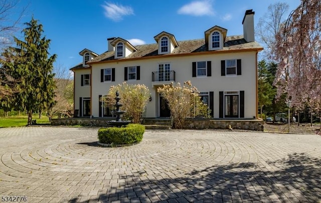 georgian-style home with a chimney and stucco siding