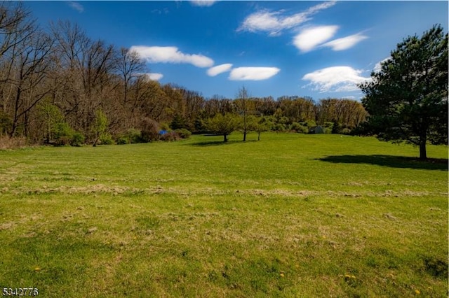 view of community with a lawn and a view of trees