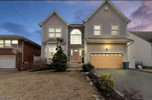 traditional-style home featuring driveway, a garage, and stucco siding