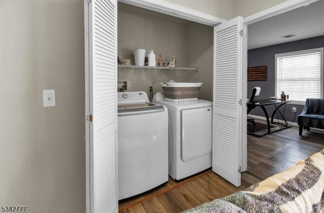 laundry area featuring laundry area, wood finished floors, washing machine and clothes dryer, and visible vents