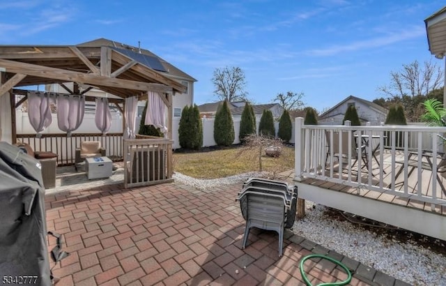 view of patio featuring a wooden deck, fence, and a gazebo