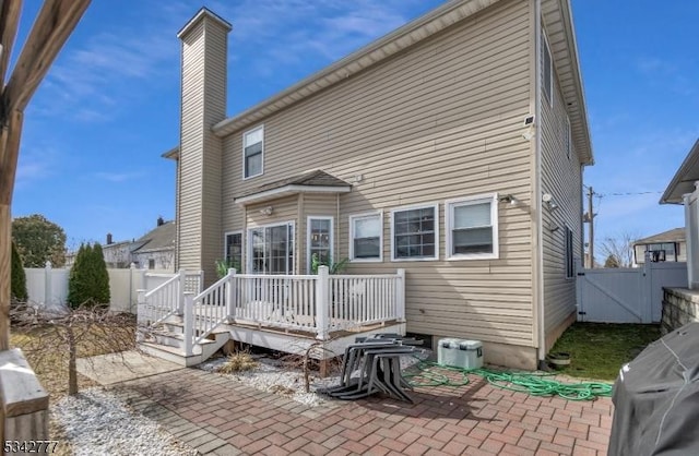 back of house with a fenced backyard, a gate, a deck, and a patio