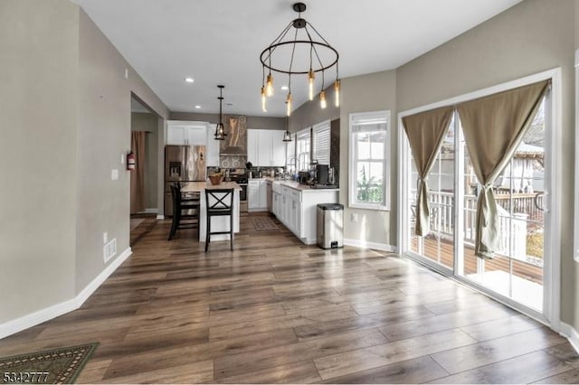 kitchen featuring stainless steel appliances, dark wood-type flooring, visible vents, white cabinetry, and wall chimney range hood