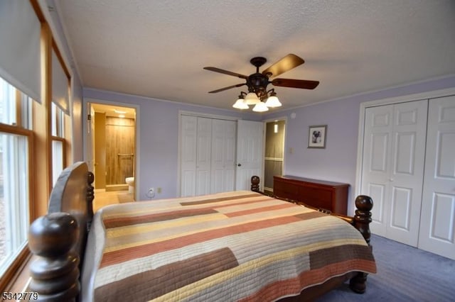 carpeted bedroom featuring multiple closets, a textured ceiling, ceiling fan, and ensuite bathroom