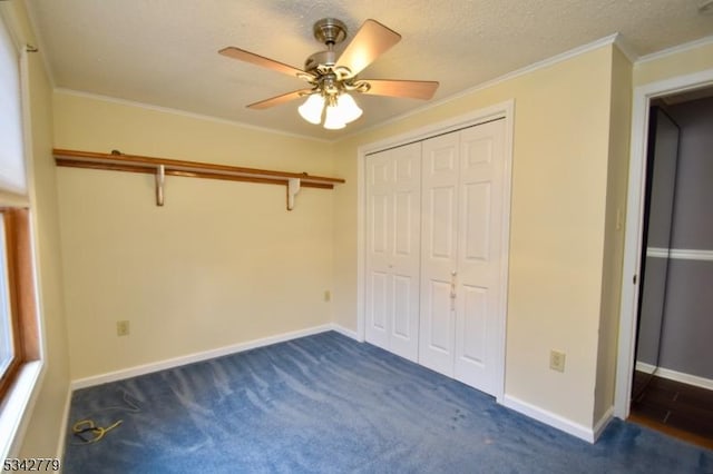 unfurnished bedroom with ornamental molding, a textured ceiling, a closet, dark colored carpet, and baseboards