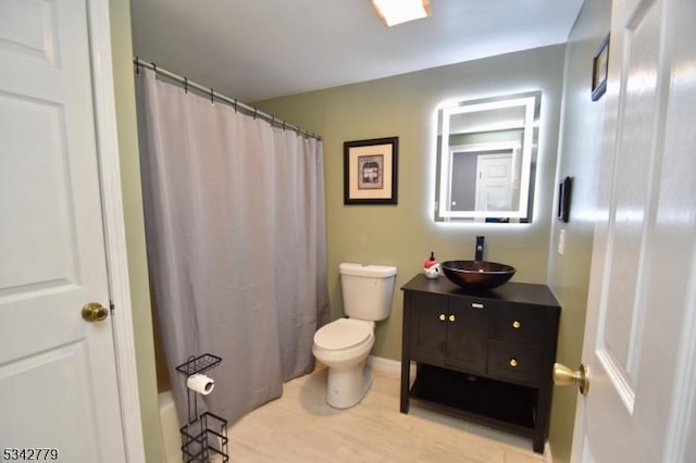 bathroom featuring curtained shower, toilet, wood finished floors, and vanity