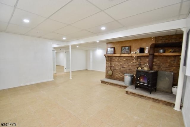 finished basement featuring recessed lighting, a drop ceiling, and a wood stove
