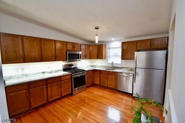 kitchen featuring a sink, brown cabinets, light wood-style floors, and appliances with stainless steel finishes