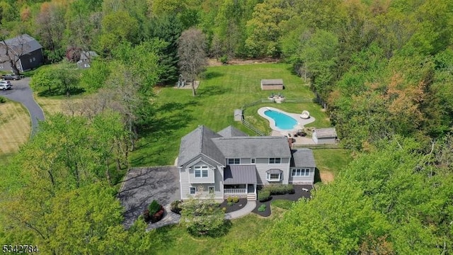 aerial view of property and surrounding area with a pool area and a heavily wooded area