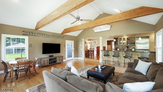 living room featuring ornate columns, light wood-style flooring, a ceiling fan, and baseboards