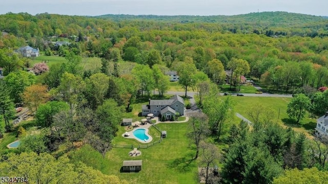 drone / aerial view of a forest and a pool area