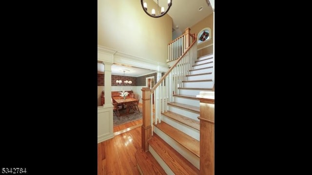 staircase with a chandelier and wood finished floors