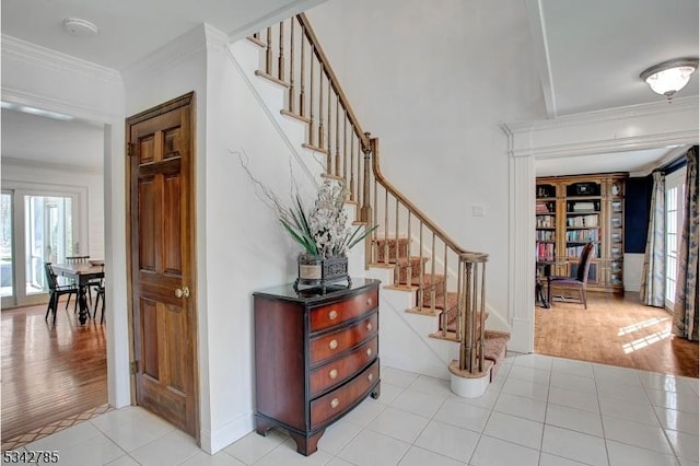 staircase with tile patterned flooring, crown molding, and baseboards