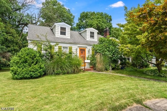 cape cod-style house featuring a shingled roof, a chimney, and a front yard