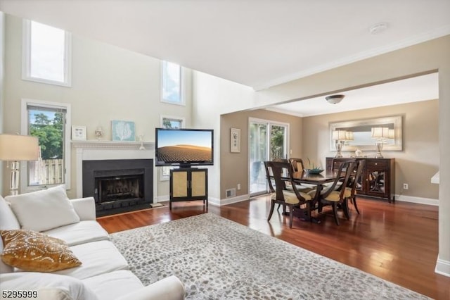 living area featuring baseboards, a fireplace with flush hearth, and wood finished floors