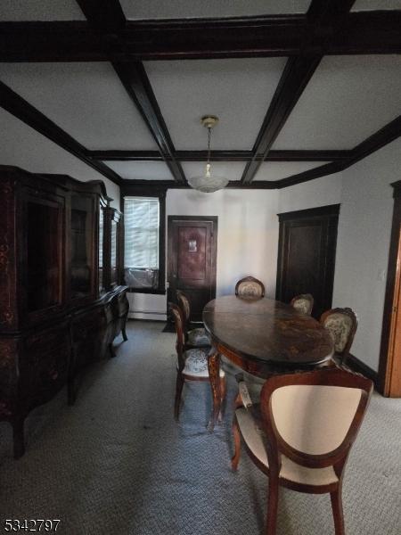 carpeted dining space with baseboards, beam ceiling, and coffered ceiling