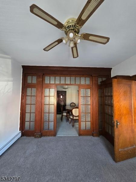 carpeted spare room featuring a baseboard heating unit, french doors, and a ceiling fan