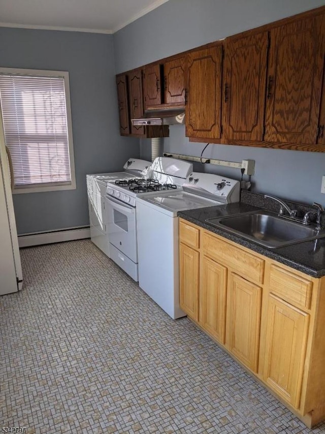 kitchen with dark countertops, crown molding, a baseboard heating unit, washer and dryer, and a sink