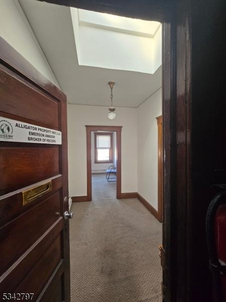 corridor featuring baseboards, carpet floors, and lofted ceiling