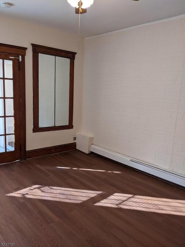 unfurnished room with crown molding, a baseboard heating unit, baseboards, and wood finished floors