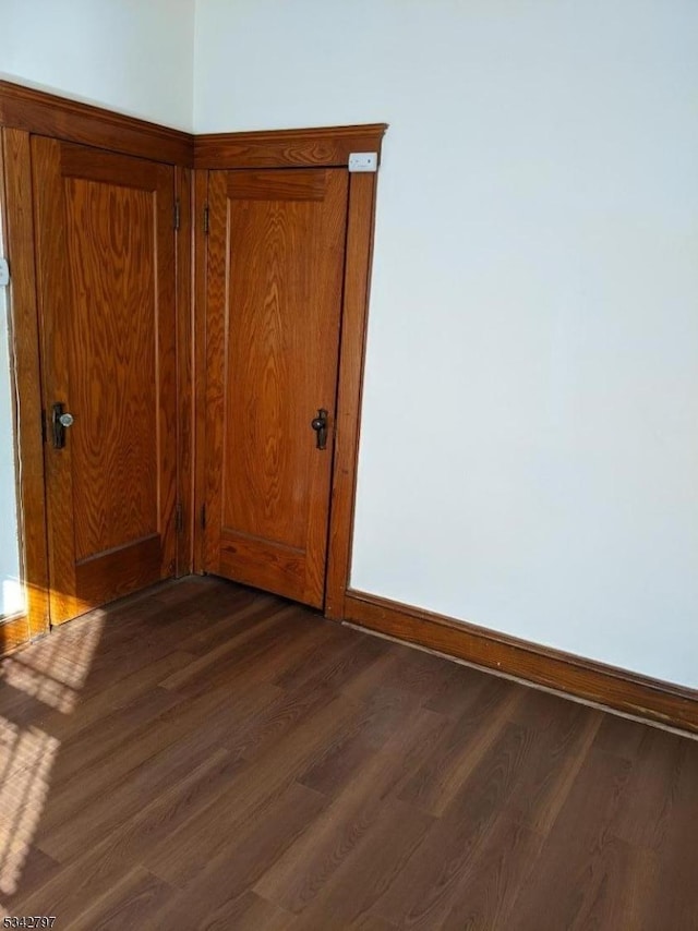 spare room with baseboards and dark wood finished floors