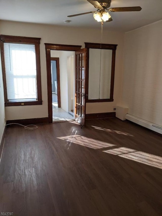 spare room featuring a baseboard radiator, a ceiling fan, baseboards, and wood finished floors