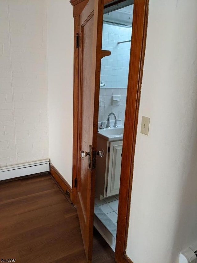 hallway with a sink, baseboards, dark wood-style flooring, and a baseboard radiator